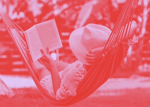 Woman with hat reading book in colorful hammock in tropical garden while relaxing in vacation.