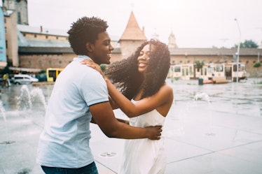 Positive emotional photo of amazing young african american couple whirling and hugging over city squ...