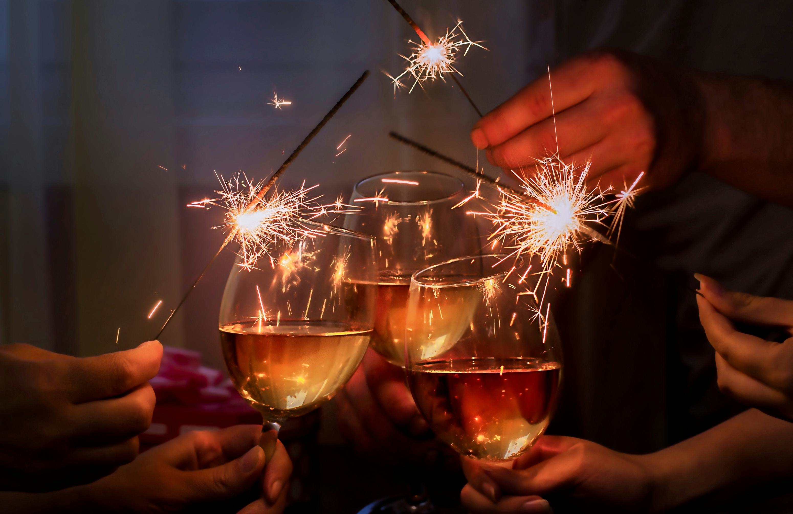 glasses with sparkling wine and sparkler is held by a company of people