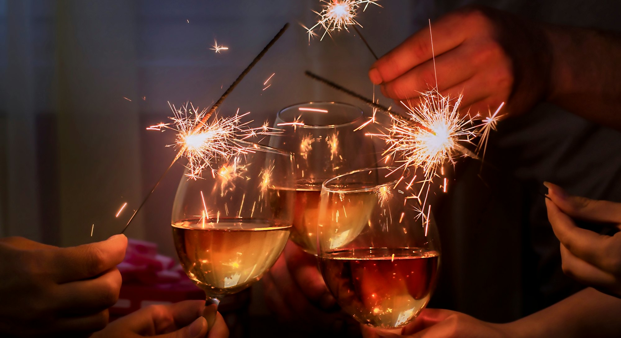glasses with sparkling wine and sparkler is held by a company of people