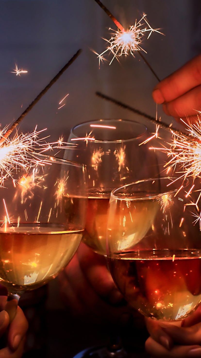 glasses with sparkling wine and sparkler is held by a company of people