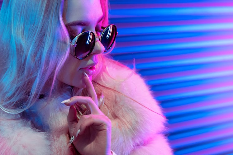 Leo woman in neon light and sunglasses to mark the end of Scorpio season 2021 and start of Sagittari...