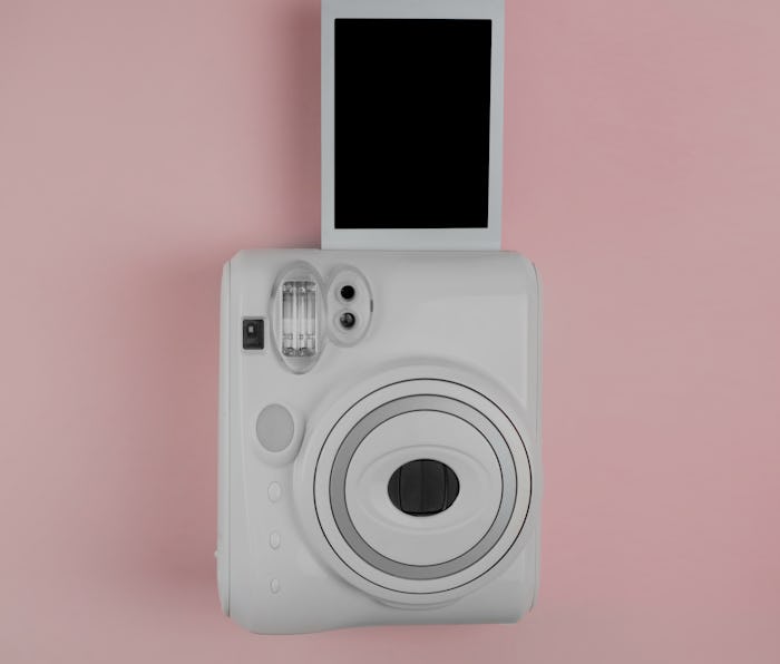 Modern instant camera, photo pink wooden background. vertical photo. retro camera. 1980s