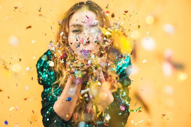 Happy fashion girl blowing confetti with yellow background - Young woman having fun at fest wearing ...