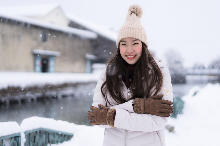 Beautiful young asian woman smile and happy with travel trip at Otaru canal Hokkaido Japan in Snow a...