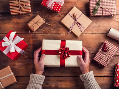 Man holding Christmas presents laid on a wooden table background