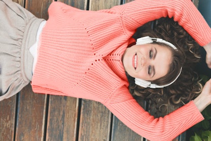 woman in fashionable clothes, in a sweater of the color of the year 2019 living coral, in headphones...