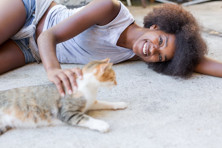 Beautiful afro american woman with her cat on the terrace. Concept of spending time with our pets an...