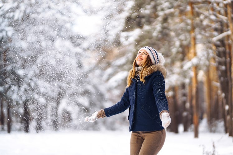 Happy young woman plays with a snow in sunny winter day. Girl enjoys winter, frosty day.  Playing wi...