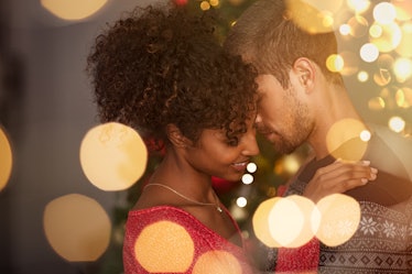 Romantic couple in sweaters dancing before new year eve at home. Young lovely man and african woman ...