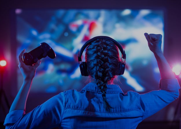 Girl in headphones plays a video game on the big TV screen. A new study has found that kids who play...