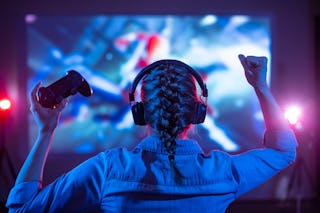 Girl in headphones plays a video game on the big TV screen. A new study has found that kids who play...