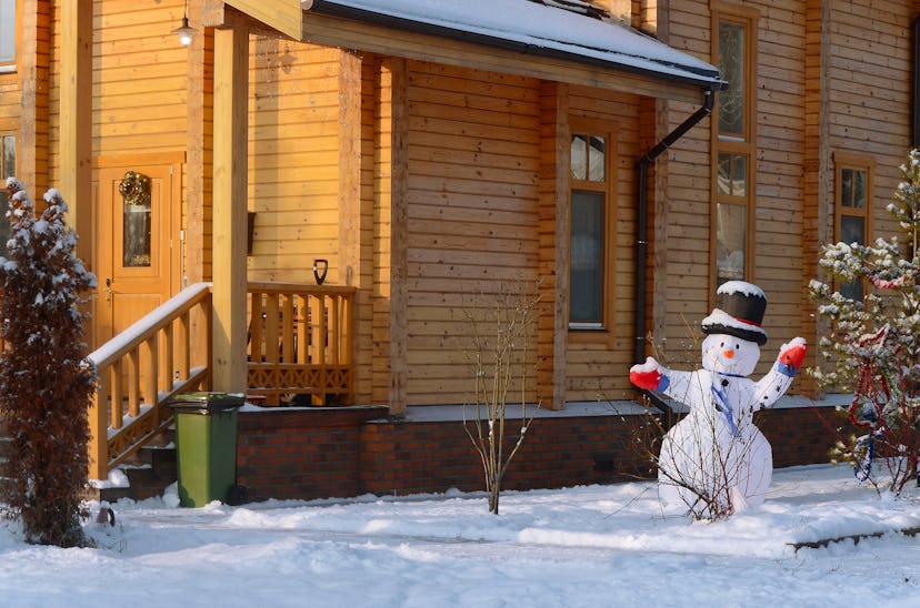 Snowman on the background of a wooden house.