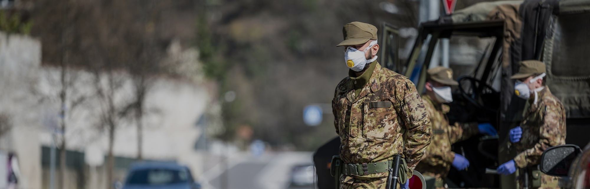 Military soldier controls on the street. Security patrol with masks and gloves monitor passing motor...
