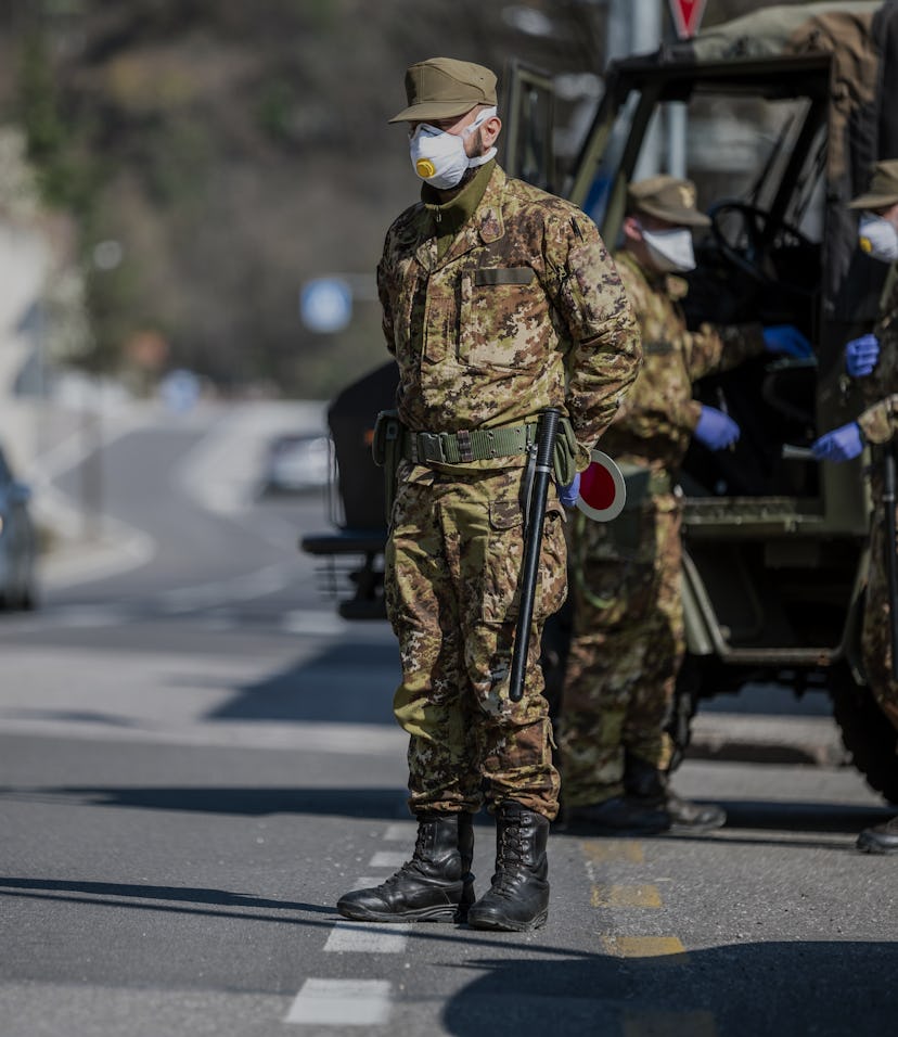 Military soldier controls on the street. Security patrol with masks and gloves monitor passing motor...