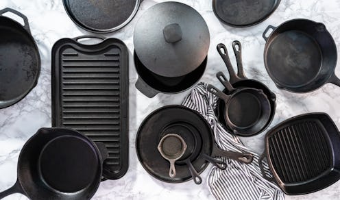 Flat lay. Variety of cast iron frying pans on a marble background.