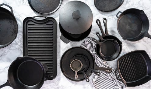 Flat lay. Variety of cast iron frying pans on a marble background.