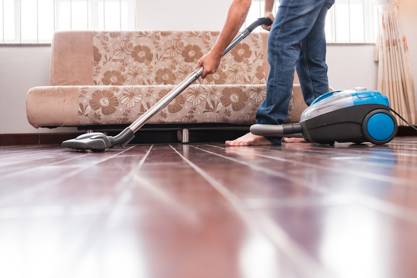 Cropped image of man vacuuming wooden floor