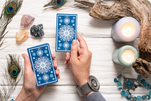 Fortune teller woman and a blue tarot cards over white wooden table background.