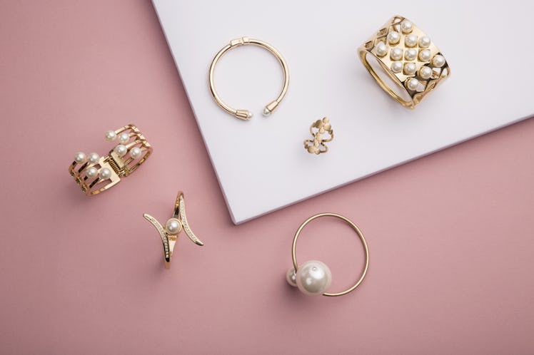 Pearl Golden Bracelets and ring on pink background - Pearl Bracelets on paper background setup