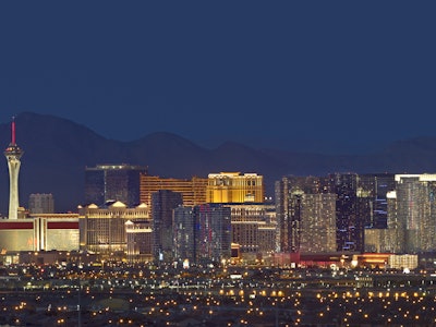Horizontal photo of Las Vegas with mountain backdrop at night.