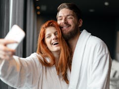 A couple poses for a selfie while wearing white robes and hanging out at a spa.