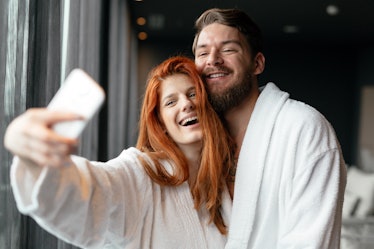 A couple poses for a selfie while wearing white robes and hanging out at a spa.