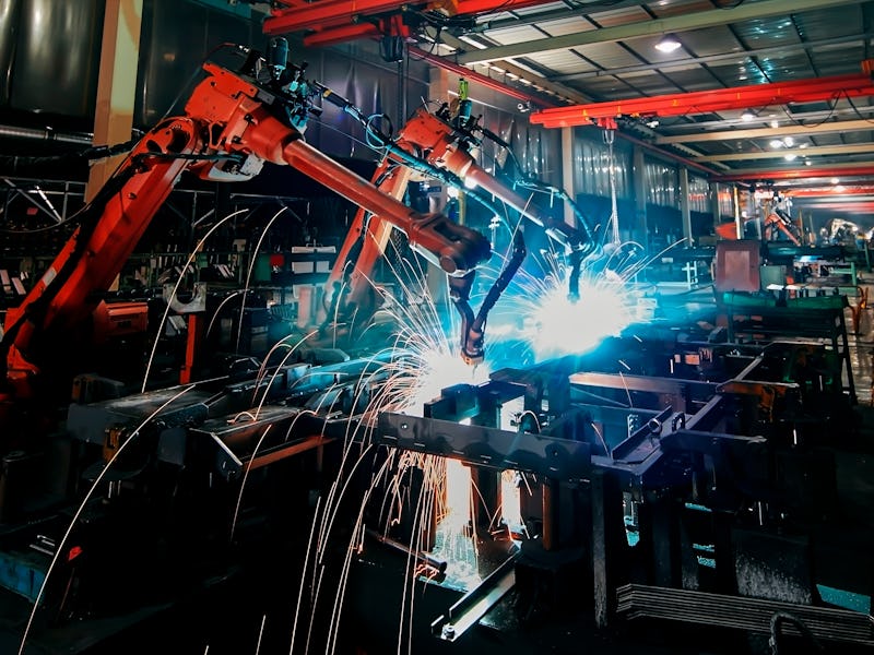 The dim large factory robotic arm is being welded and assembled
