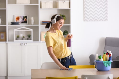 Young woman listening to music while cleaning her flat
