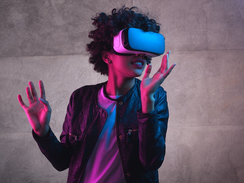 Cheerful girl with hands up wearing the virtual reality goggles.