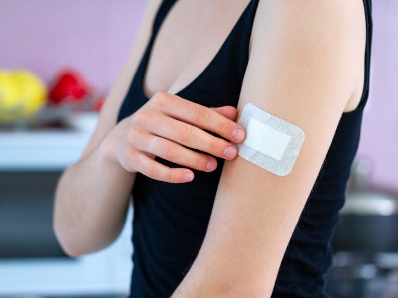 Woman using a medical adhesive bandage on arm after vaccination, injection vaccine or medicine. Firs...