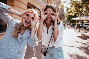 Lovely girl with blonde hair chilling outdoor with friend. Photo of brunette lady having fun with si...