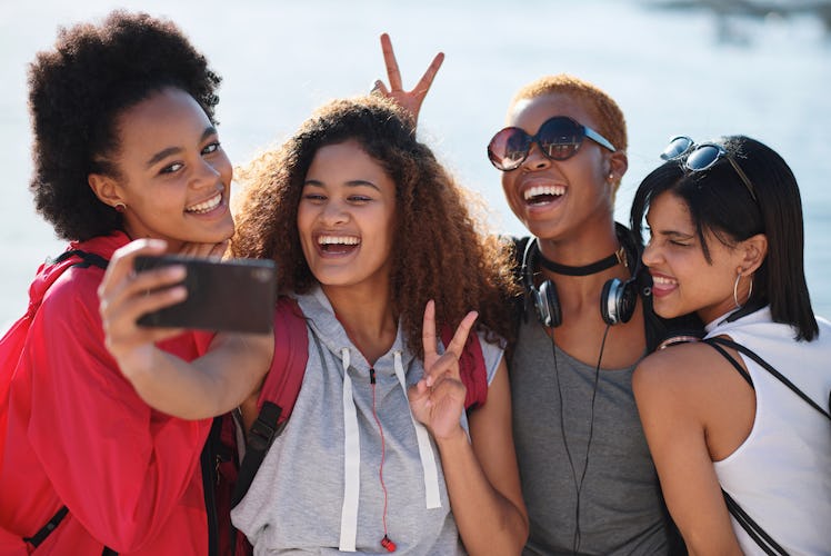 Female friends smile and pose for a selfie on a sunny afternoon.