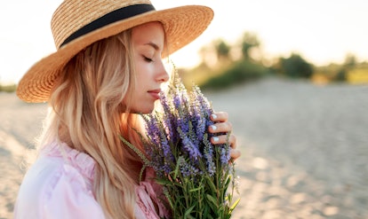 Romantic close up portrait  o charming blonde girl in straw hat  smells    flowers   on   the eveni...