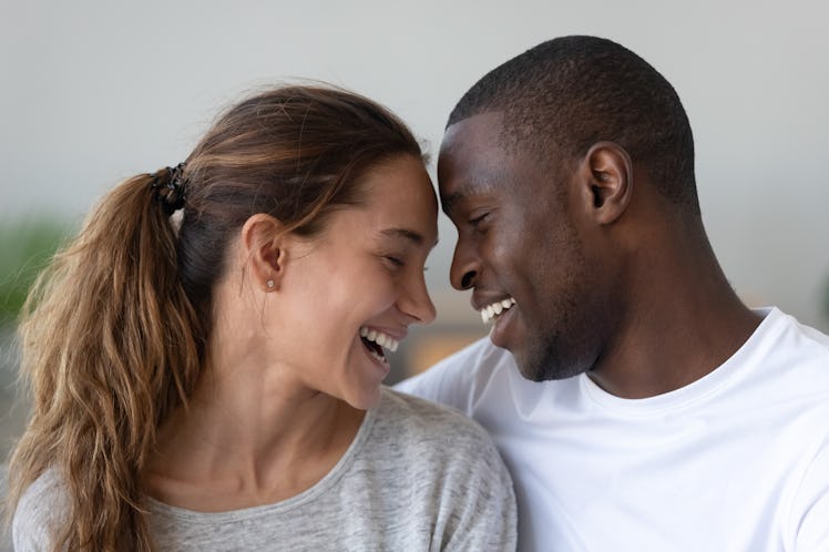 Head shot multiracial young married spouse laughing, cuddling hugging embracing bonding together, to...
