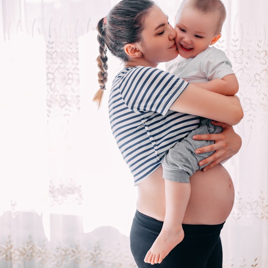 Beautiful pregnant woman and her toddler son. Young mother waiting of a second baby. Pregnancy and f...