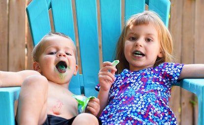Two toddlers eating candy with blue tongues