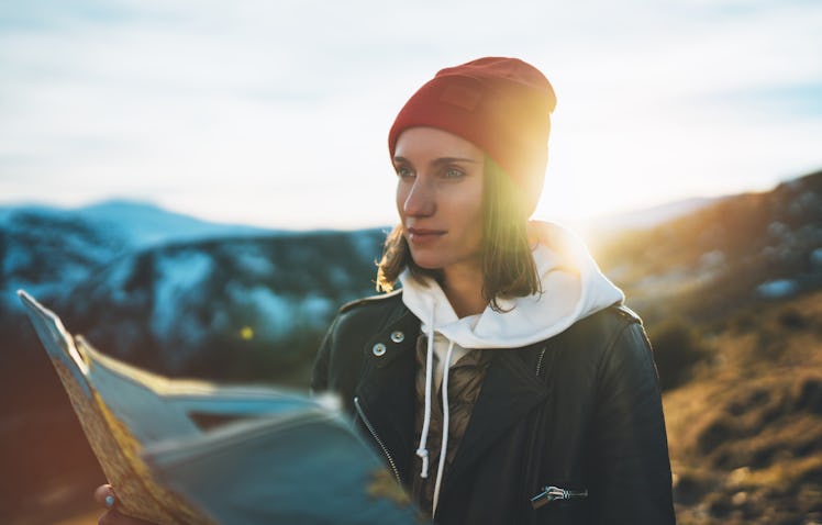 young girl look and hold in hands map, people planning trip, hipster tourist on background sun flare...