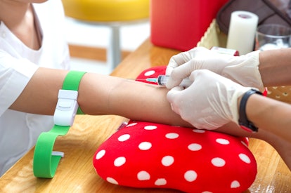 Close up nurse pricking needle syringe in the arm patient drawing blood sample for blood test