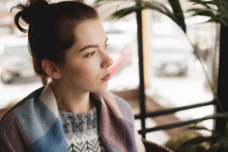 Woman in pullover sadly looking at window in a cafe