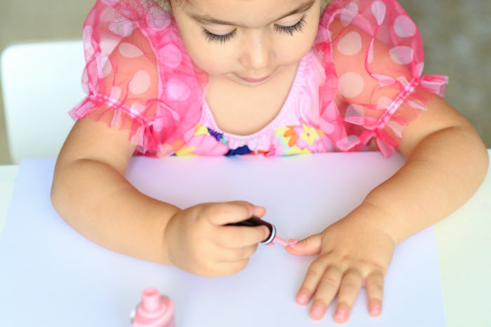 a little girl painting her nails with pink nail polish