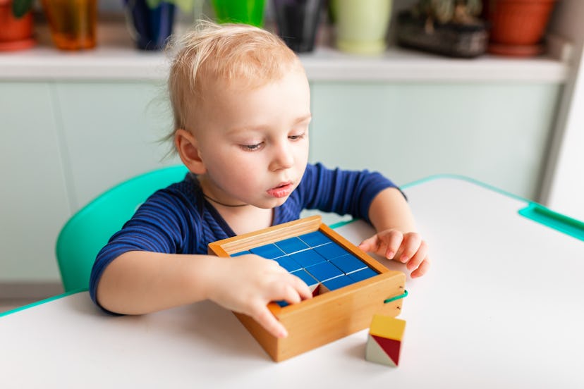 Baby playing with wooden blocks creating a pattern. Nikitin unicube game