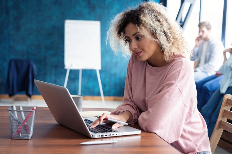 Beautiful business African lady is looking at camera and smiling while working in office. Attractive...