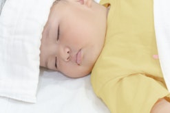 Sick baby girl sleeping with white towel at head reducing temperature