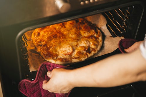 girl pulls pizza out of the oven