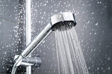 Fresh shower behind wet glass window with water drops splashing. Water running from shower head and ...