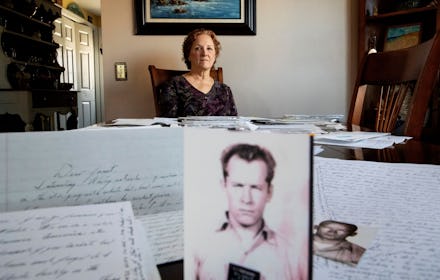 Janet Uhlar sits for a photo at her dining room table with an arrangement of letters and pictures sh...