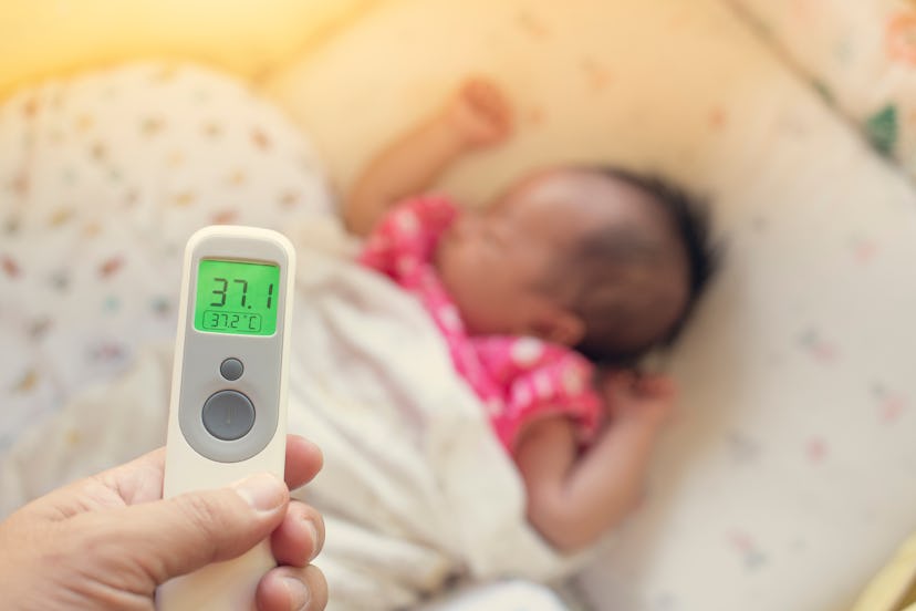 Hand holding digital infared thermometer to measure or check for her son illness and flu fever while...