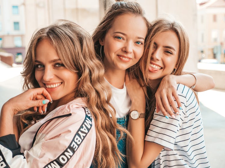 Portrait of three young beautiful smiling hipster girls in trendy summer clothes. Sexy carefree wome...