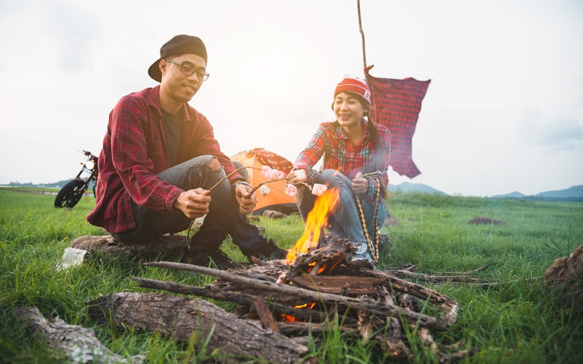 Couple lover enjoying roasting marshmallows over the fire, couple lover enjoy camping countryside wi...